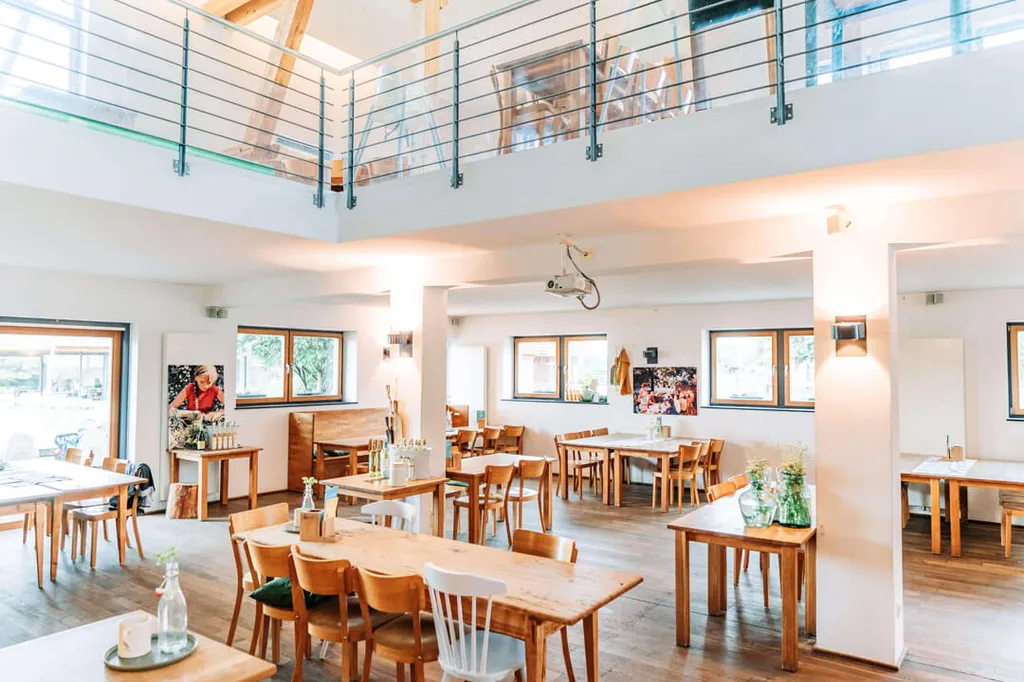 Jasna sala restauracyjna z drewnianymi stołami w Gut Hügle