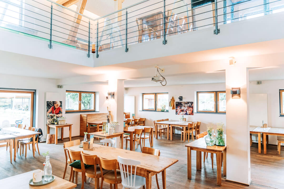 Jasna sala restauracyjna z drewnianymi stołami w Gut Hügle